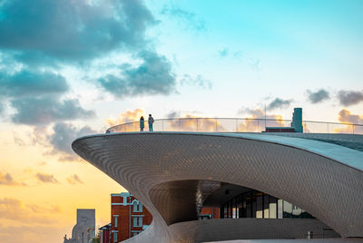 Low angle view of bridge and buildings against sky during sunset