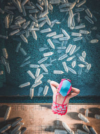 Directly above shot of girl standing by plastic bottles in swimming pool