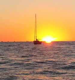 Sailboat sailing on sea against sky during sunset