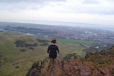 Rear view of man standing on mountain by sea against sky