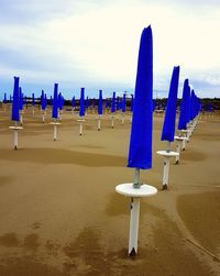 Row of deck chairs on beach against sky