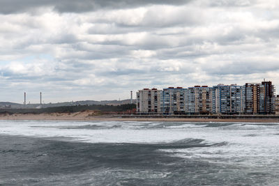 Sea and buildings in city against sky