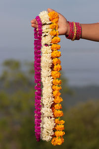 Cropped hand of woman holding floral garland outdoors