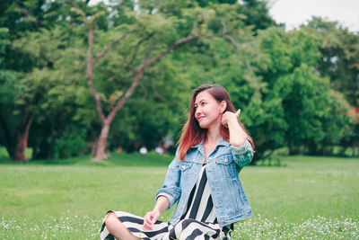 Portrait of smiling young woman using phone on field