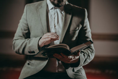 Midsection of man reading book