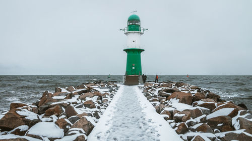 Lighthouse by sea against sky