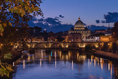 Illuminated bridge over river in city against sky