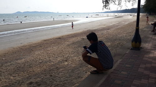 Rear view of man sitting on beach