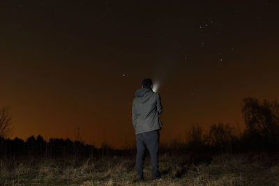 Rear view of man standing on field at night