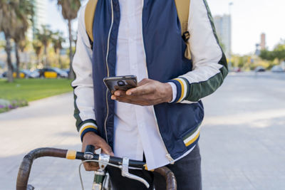 Close-up of casual businessman with bicycle using cell phone in the city, barcelona, spain