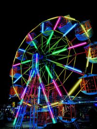 Low angle view of illuminated ferris wheel against sky at night