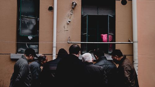 Rear view of people walking in front of building
