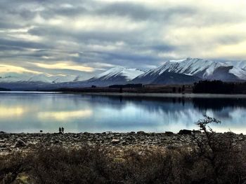 Scenic view of lake and mountains against cloudy sky