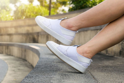 Low section of woman wearing canvas shoes sitting on steps