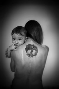 Rear view of shirtless girl against gray background