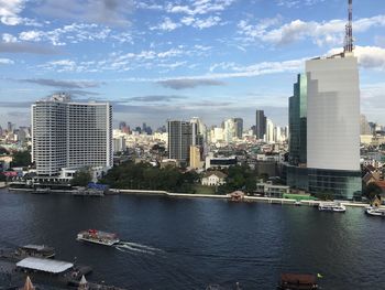 City at waterfront against cloudy sky