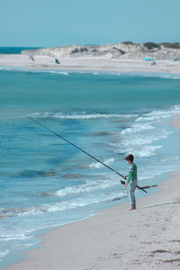 Full length of two children fishing on beach