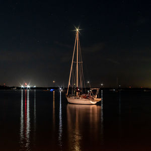 Sailboats in sea against sky at night