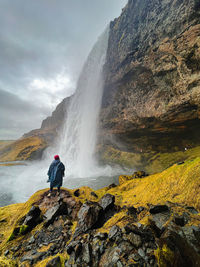 Rear view of man standing against waterfall