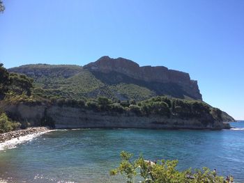 Scenic view of sea and mountains against clear blue sky