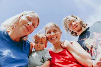 Low angle portrait of smiling family against sky