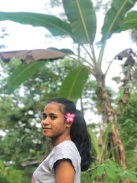 Young woman looking away against plants