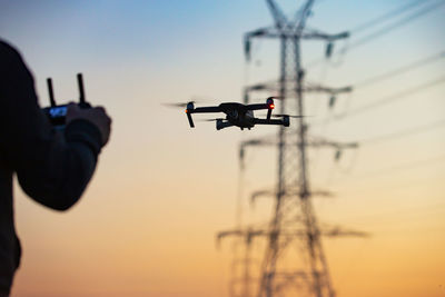 Drone pilot operating an uav in proximity to electric pylons and energy lines.