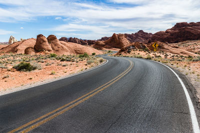 Road by desert against sky