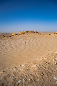 Surface level of sand on beach against clear blue sky