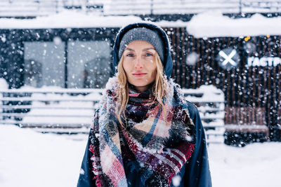 Portrait of a beautiful thirty-year-old european woman in a hood in a snowfall.