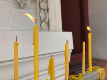 Yellow candles on wooden door of temple