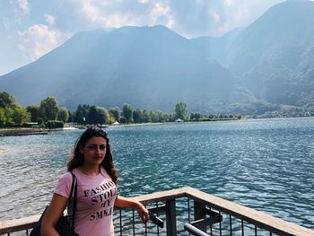 Portrait of young woman by lake against mountains