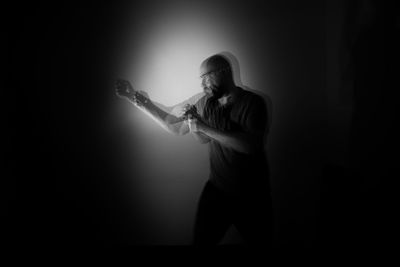 Young man standing against black background