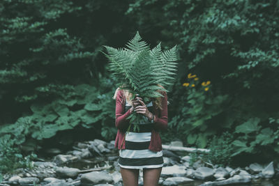 Woman holding fern leaf in forest