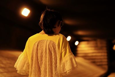 Rear view of girl standing outdoors at night