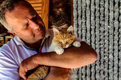 Close-up of man holding cat at home