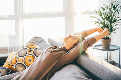 Low section of woman relaxing on bed at home