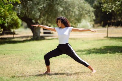 Woman stretching body on field against trees