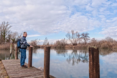 Man standing by lake against sky