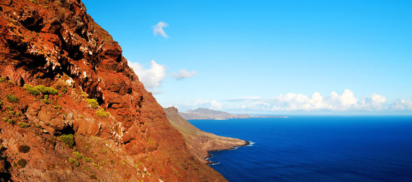 Scenic view of rocky mountains by sea against sky at gran canaria island