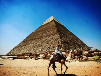 Man riding camel against pyramid