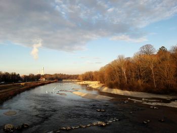 Frozen river in city against sky during winter