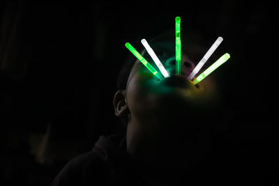 Close-up portrait of illuminated light bulb over black background