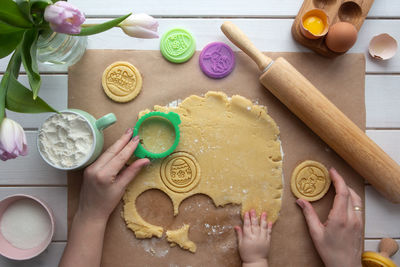 Flat lay with mother and baby hands preparing easter theme cookies. spring holidays and family time