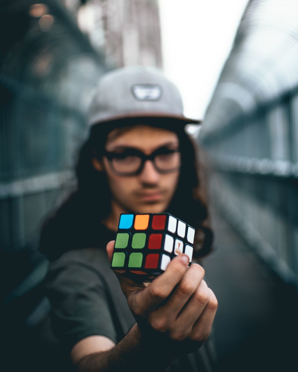 glasses, real people, one person, portrait, young adult, lifestyles, holding, leisure activity, focus on foreground, eyeglasses, front view, casual clothing, waist up, looking at camera, day, men, standing, hat