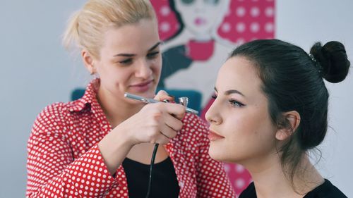 Beautician doing make-up of woman
