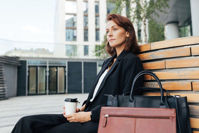 Portrait of young woman using mobile phone in city