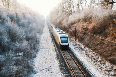 Train on railroad tracks with driving passenger train during winter