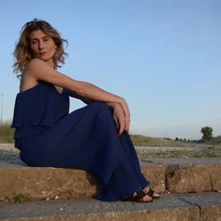 Portrait of woman sitting on steps against clear blue sky