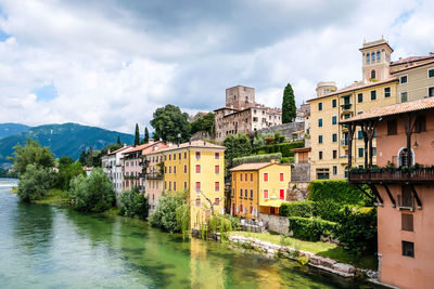 Buildings by river against sky